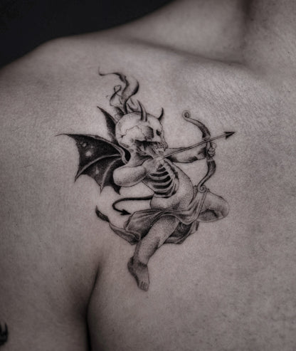 A detailed black and gray tattoo of a skeletal cupid with bat wings playing a bow on a person's upper shoulder.